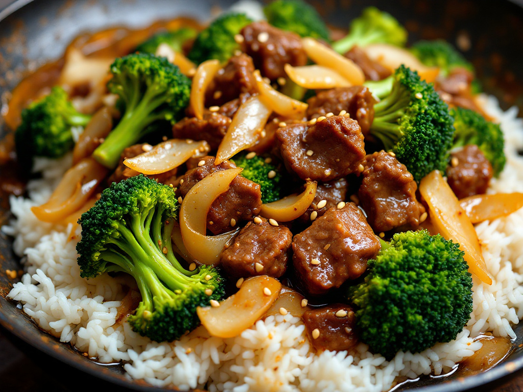 A sizzling skillet filled with beef and broccoli stir-fry, with visible chunks of ground beef, broccoli florets, and sliced onions, coated in a glossy sauce, served over a bed of steamed rice.