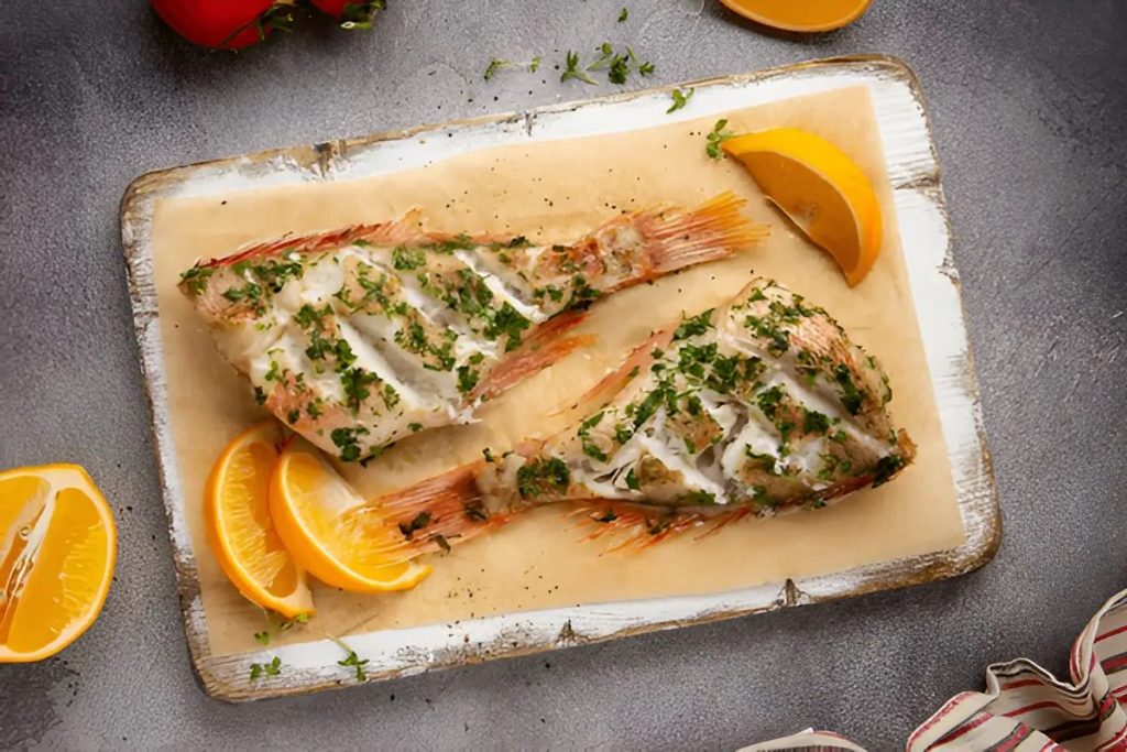 Baked whole rockfish garnished with lemon slices and fresh herbs. Rockfish Recipes.