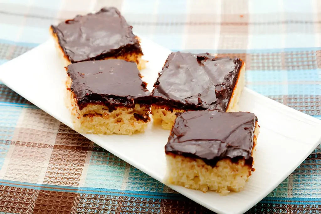 Homemade Tandy Cake Recipe slices arranged on a white plate, featuring a smooth chocolate topping over a moist yellow cake base.