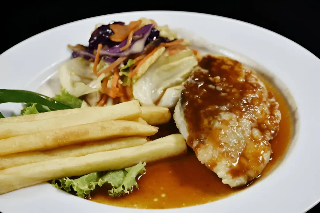 A plate featuring a breaded and fried fish fillet with sauce, accompanied by fries and coleslaw.