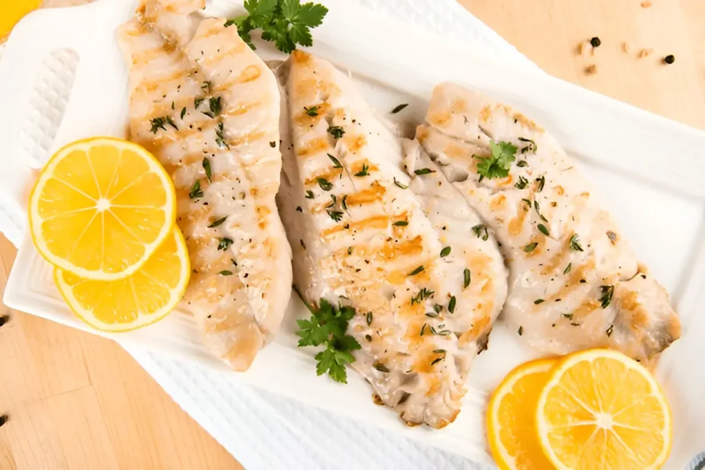 Grilled rockfish fillets garnished with lemon slices and fresh herbs. Rockfish Recipes.