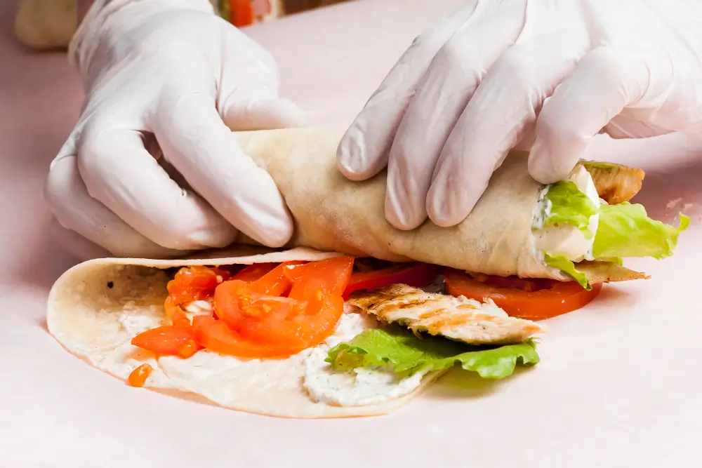 A close-up of a delicious shrimp wrap recipe being prepared, showcasing fresh ingredients like lettuce, tomatoes, and a creamy sauce, all wrapped in a soft tortilla.