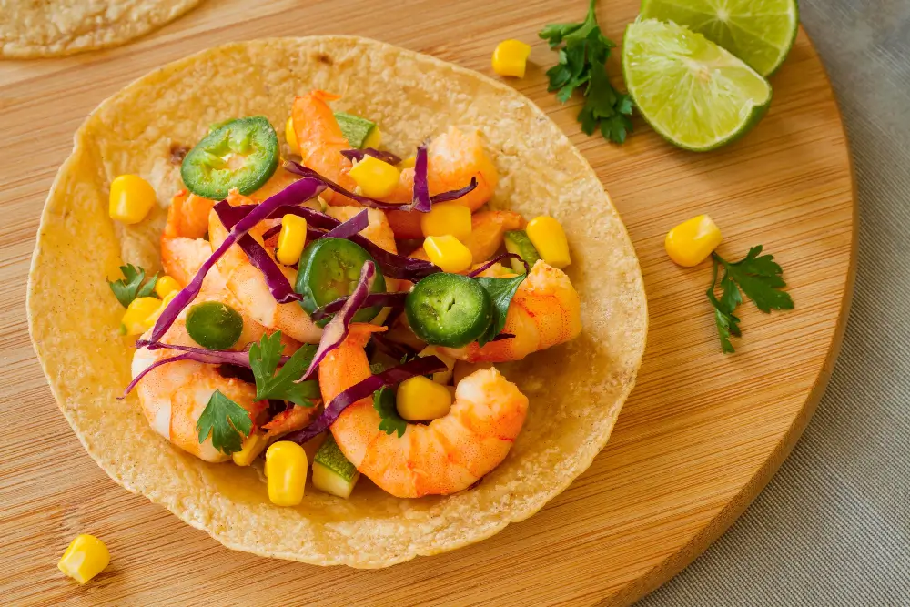 A delicious shrimp wrap recipe featuring succulent shrimp, colorful vegetables, and a sprinkle of fresh herbs on a wooden cutting board.