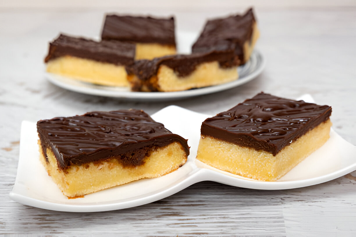 Delicious Tandy Cake Recipe slices on white plates, showcasing the rich chocolate topping and fluffy yellow cake base.