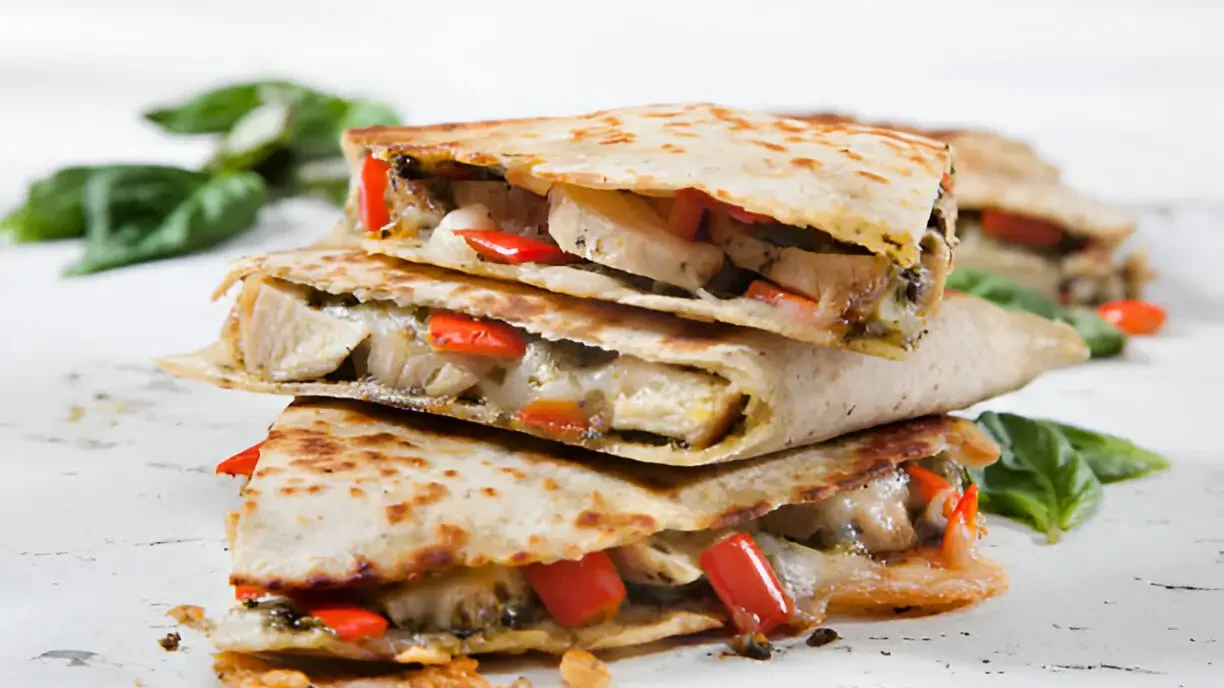 Delicious Chicken Quesadillas with melted cheese, grilled chicken, and colorful peppers, served on a rustic wooden board.