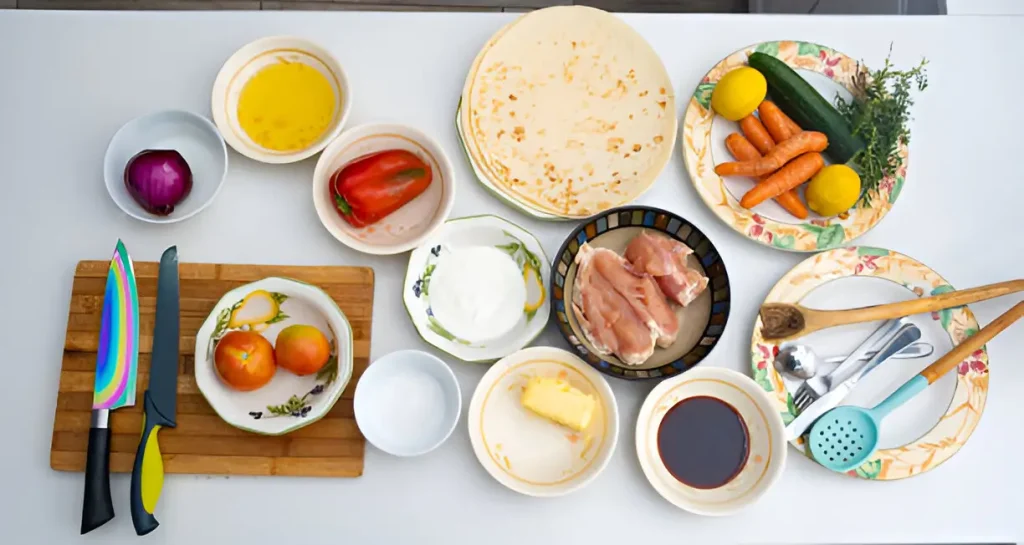 Ingredients and utensils laid out on a kitchen counter for making Chicken Quesadillas, including tortillas, chicken, vegetables, cheese, and seasonings.